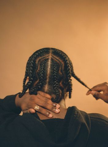 Hands sectioning and braiding a client's hair